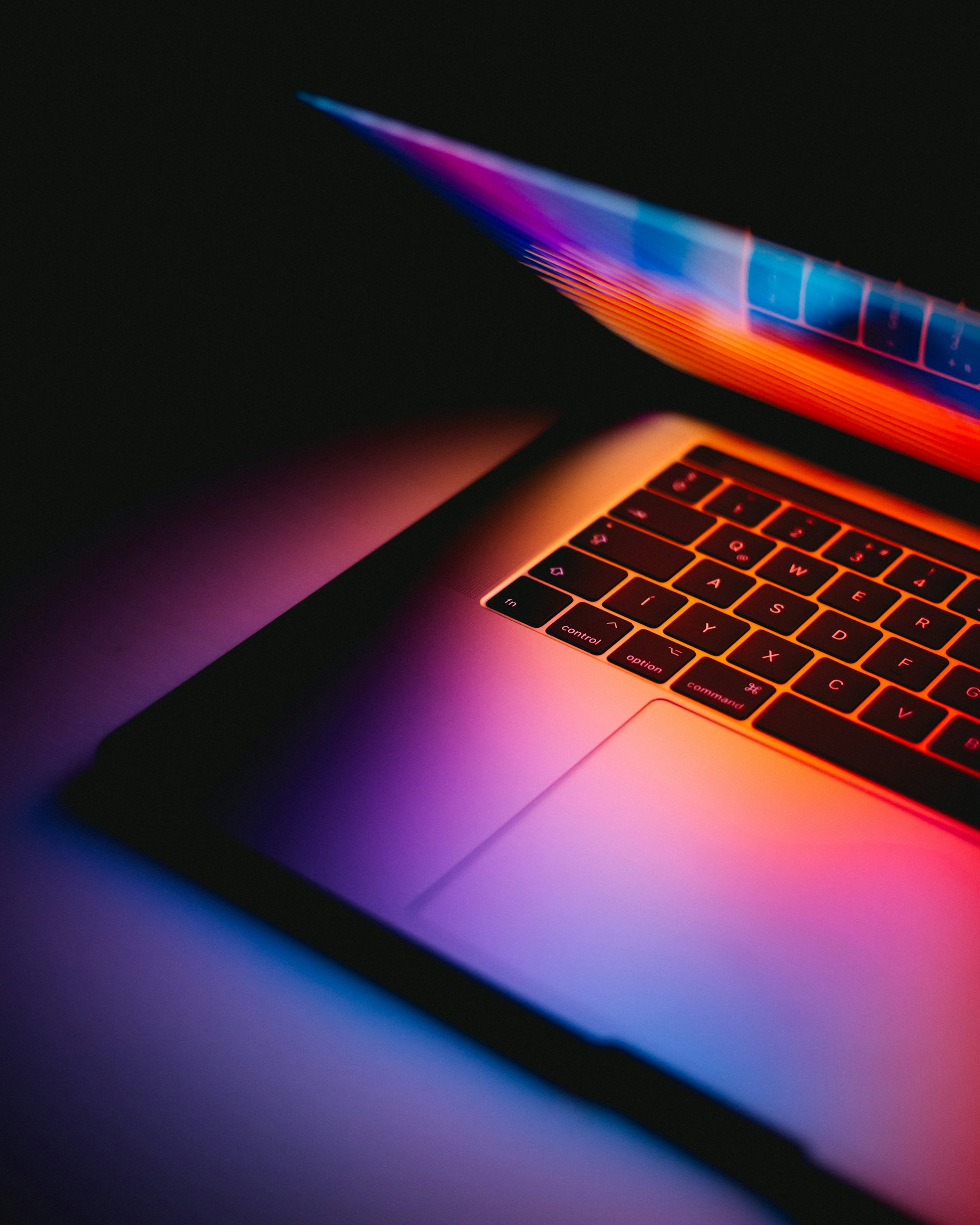 mac laptop keyboard lit by particially closed screen
